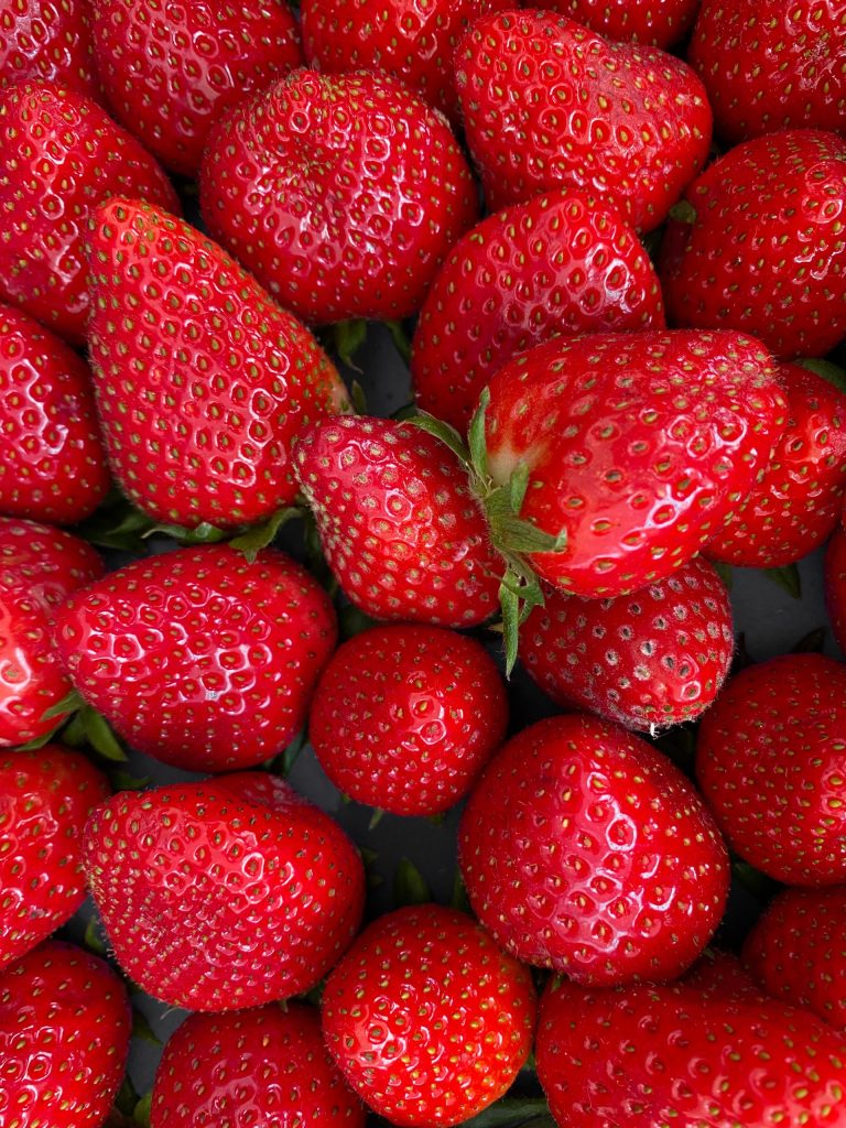 vertical closeup shot of vibrant red juicy fresh strawberries background